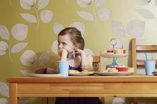 Fille à la recherche ennuyée à table avec de la nourriture de fête — Photo de stock