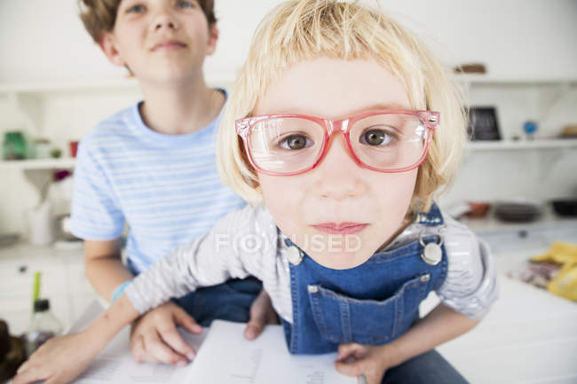 Portrait of cute girl in eye glasses with brother in kitchen — Stock Photo