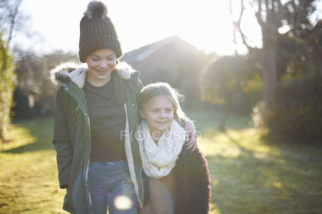 Siblings enjoying sun in garden together during cold weather — Stock Photo
