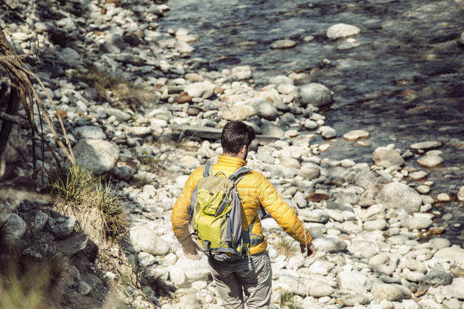 Visão traseira do jovem caminhante do sexo masculino que desce para o rio Toce, Vogogna, Verbania, Piemonte, Itália — Fotografia de Stock