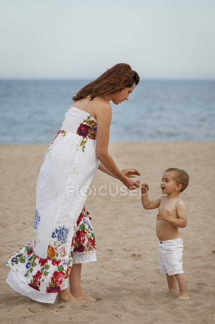 Mãe e criança de pé na praia — Fotografia de Stock