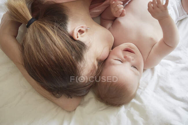 Visão aérea da mulher na cama beijando bebê filho na bochecha — Fotografia de Stock