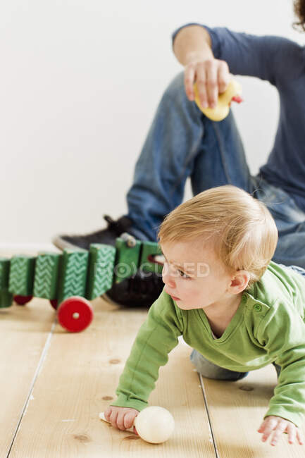 Studio shot of father and baby daughter playing on floor — Stock Photo