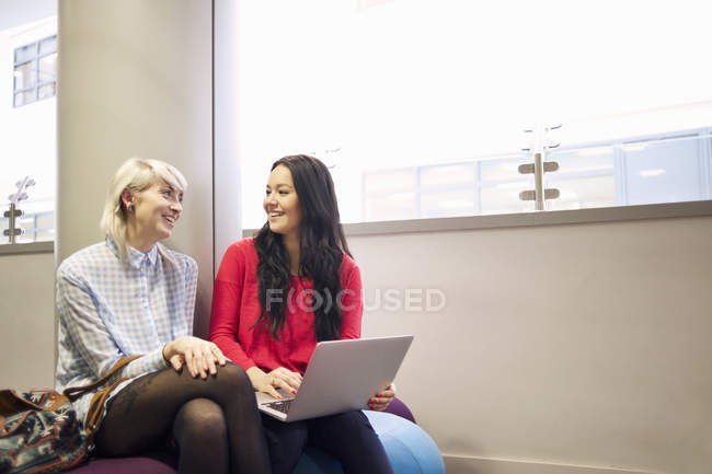 Two young women using laptop in university campus building — Stock Photo