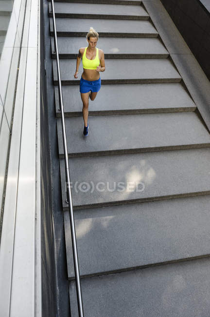 High angle view of female jogger running down steps — Stock Photo
