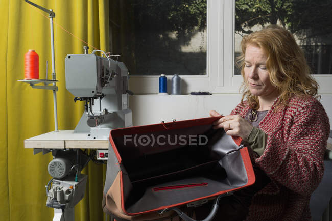 Woman at sewing machine assembling leather holdall — Stock Photo