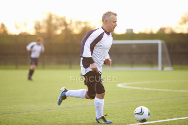 Jogador de futebol com posse de bola no campo — Fotografia de Stock