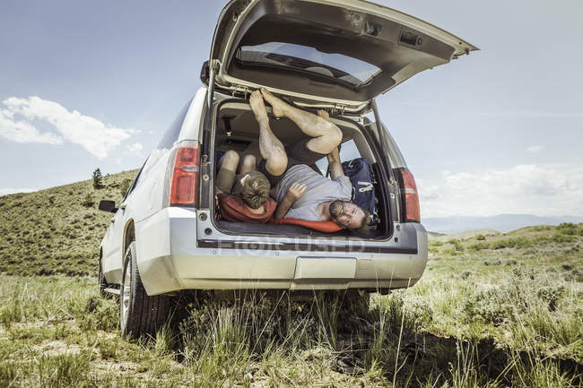Hombre maduro e hijo adolescente saliendo del vehículo todoterreno, Bridger, Montana, EE.UU. - foto de stock