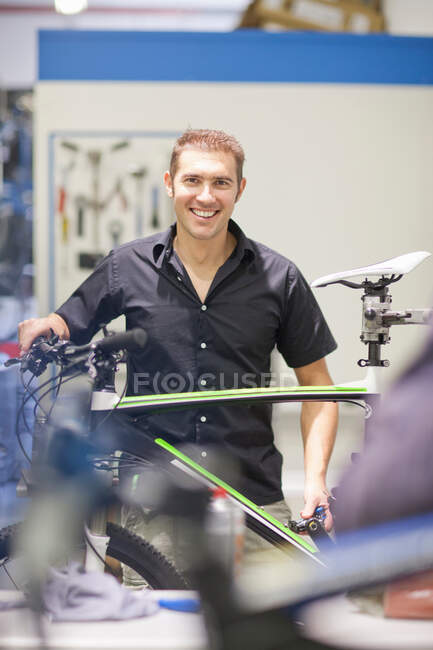 Середній дорослий чоловік у ремонтному магазині з велосипедом — стокове фото