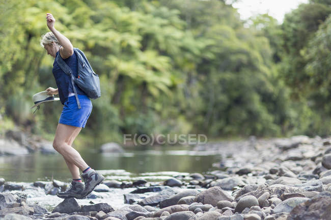 Escursionista a piedi tra le pietre in torrente poco profondo, Waima Forest, Isola del Nord, NZ — Foto stock