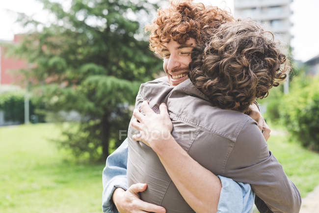 Male Friends hugging in park together — Stock Photo
