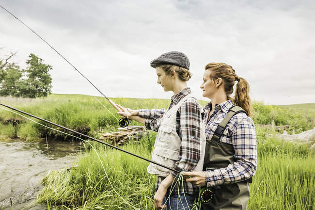 Вид сбоку на мать и дочь, ловящие рыбу в реке — стоковое фото