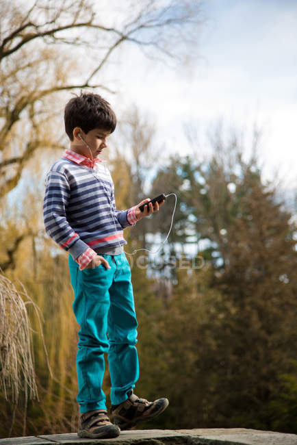 Хлопчик грає на смартфоні на ігровому майданчику — стокове фото