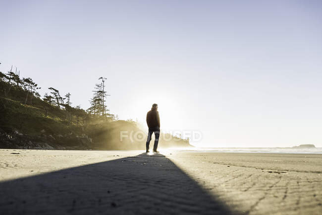 Hombre mirando desde Long Beach al amanecer, Pacific Rim National Park, Vancouver Island, Columbia Británica, Canadá - foto de stock