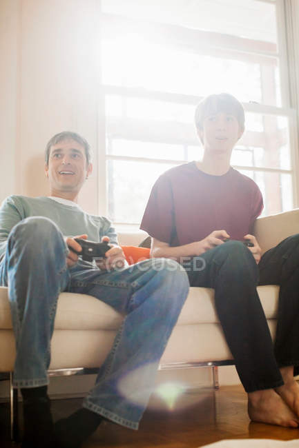 Father and son playing video game on sofa — Stock Photo