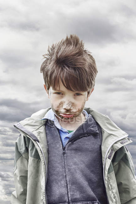 Elementary age boy with muddy face outdoors — Stock Photo
