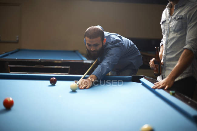 Mann spielt Pool, Freund mit Bier im Vordergrund — Stockfoto