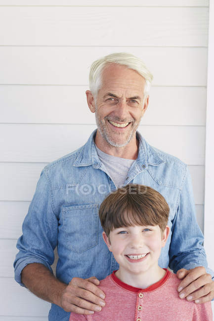 Retrato de niño y abuelo mirando a la cámara sonriendo - foto de stock