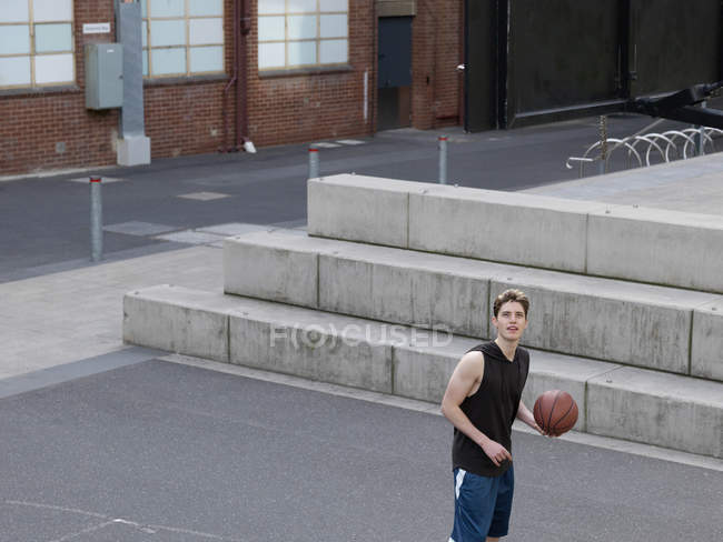 Молодой человек играет в баскетбол на открытой площадке — стоковое фото