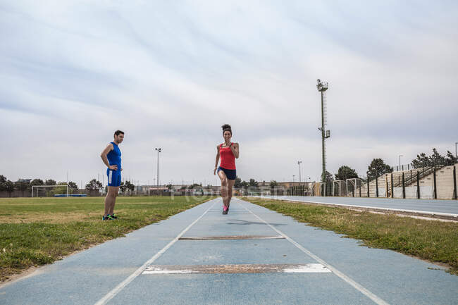 Mujer joven salto largo entrenamiento de sprint en las instalaciones deportivas - foto de stock