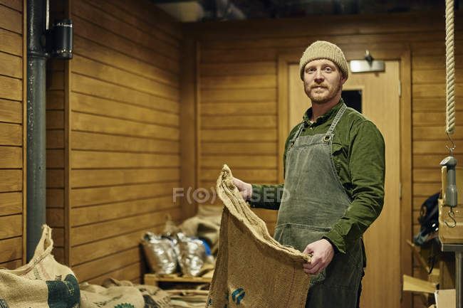 Coffee shop worker posing with coffee sack — Stock Photo