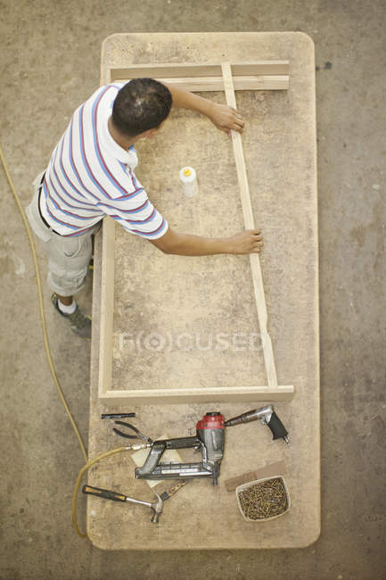 Upholsterer construindo uma moldura de madeira na mesa — Fotografia de Stock