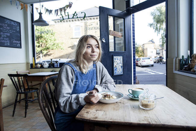 Mujer joven en la cafetería, comiendo muesli - foto de stock