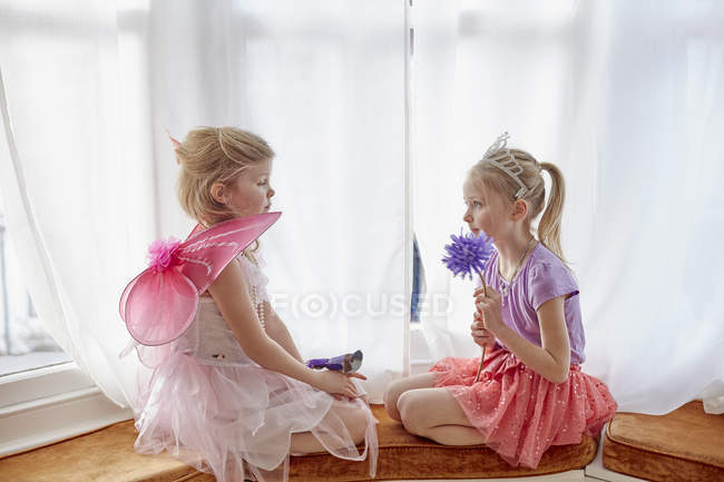 Две молодые девушки, в маскарадной одежде, сидя лицом к лицу — стоковое фото
