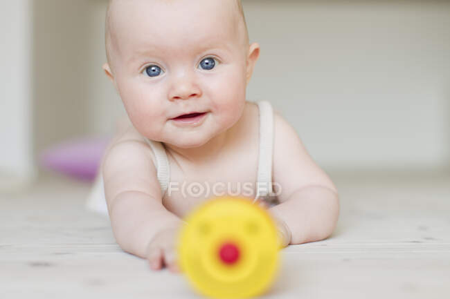 Bébé fille avec jouet au premier plan — Photo de stock