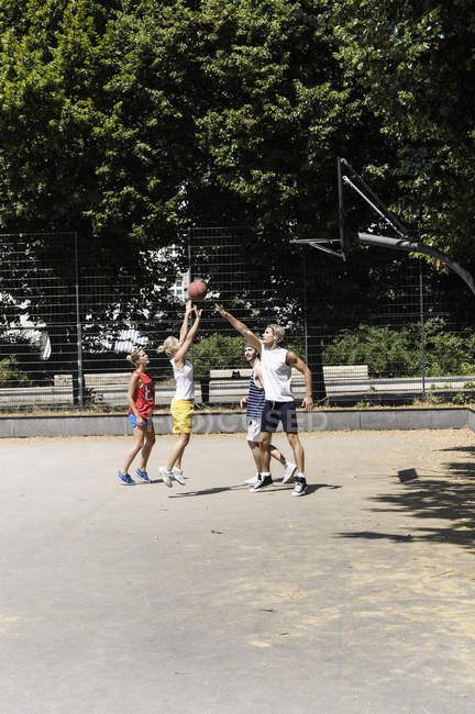Gruppo di amici che giocano a basket in campo nel parco — Foto stock