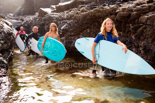 Four people carrying surfboards — Stock Photo