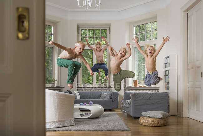 Chicos en la sala de estar saltando en el aire - foto de stock