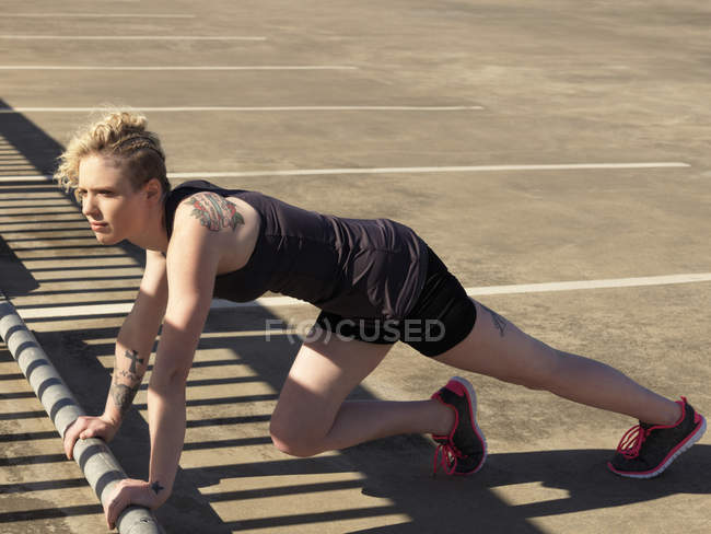Young woman doing push up training in urban parking lot — Stock Photo