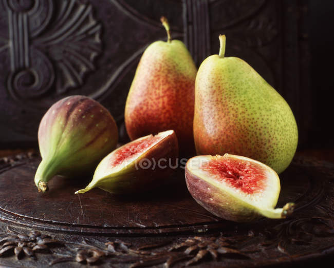 Ripe pears and figs on wooden chopping board — Stock Photo