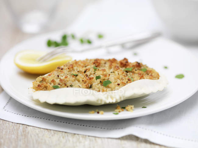 Crab gratin in shell with lemon slice and fork on plate — Stock Photo