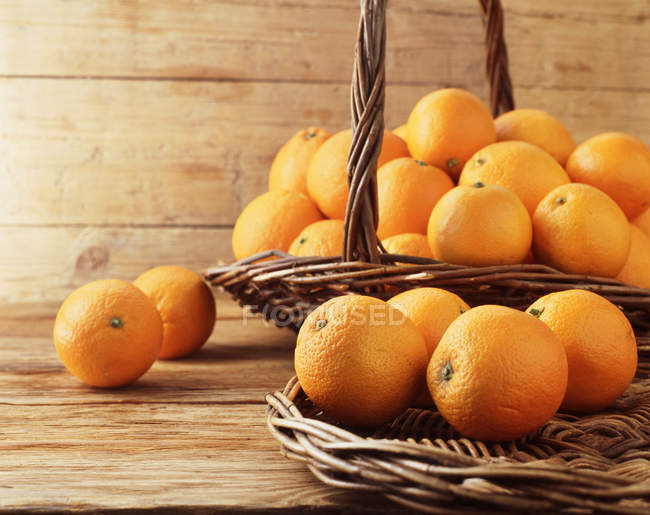 Апельсины в плетеной корзине и на плетеной тарелке — стоковое фото