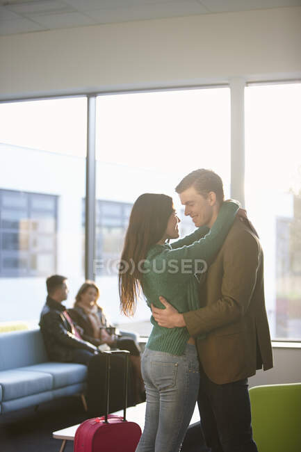 Молодая пара обнимается в аэропорту — стоковое фото