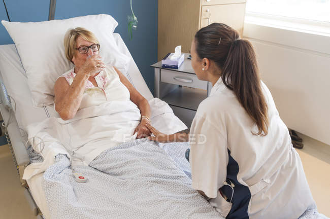 Nurse helping patient in hospital bed — Stock Photo