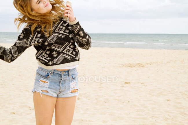 Молодая женщина танцует под MP3-плеер на пляже — стоковое фото