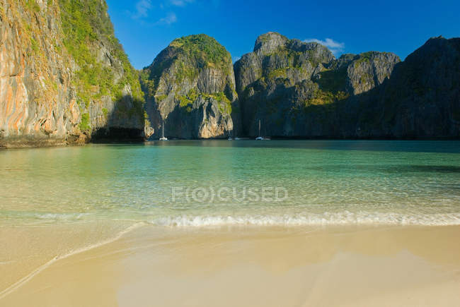 Waves washing up on sandy beach with green hills — Stock Photo