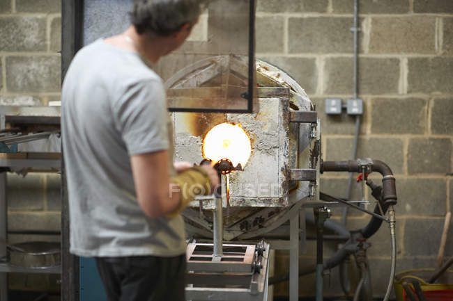 Male caucasian Glassblower in workshop using furnace — Stock Photo