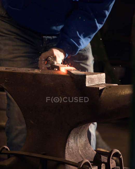 Farrier forching horseshoe on anvil — стоковое фото