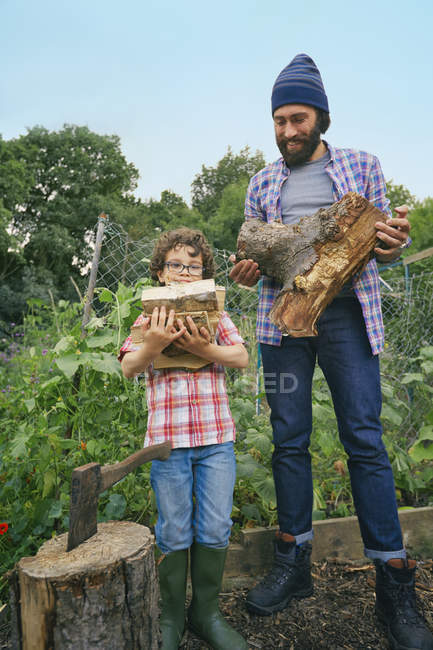 Father and son with chopped logs on allotment — Stock Photo