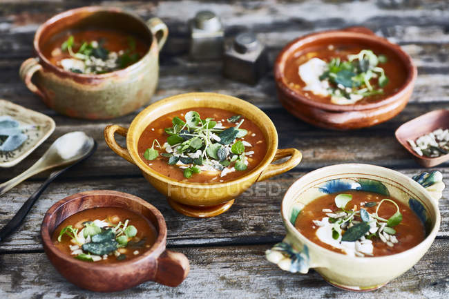 Bowls of garnished soup on wooden table — Stock Photo