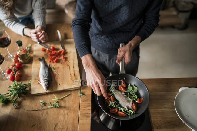 Cropped image of couple preparing fish at kitchen counter — Stock Photo