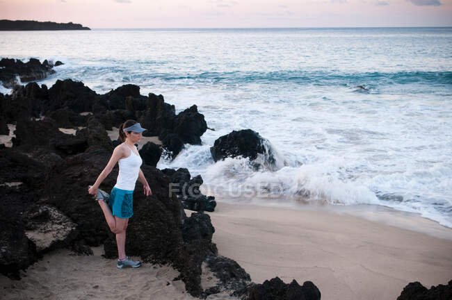 Runner stretching on beach — Stock Photo