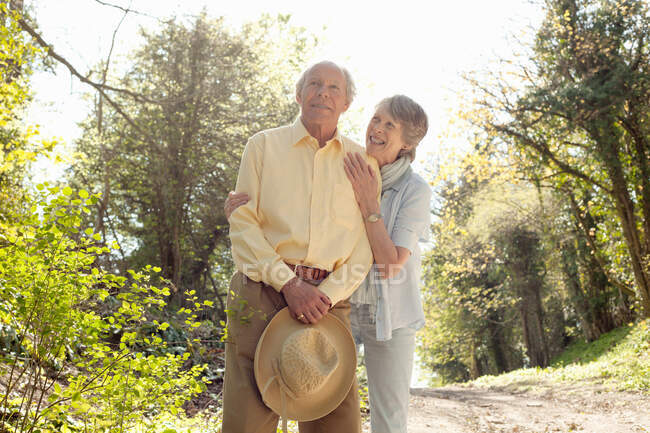 Esposa posando com o marido segurando seu chapéu de palha — Fotografia de Stock