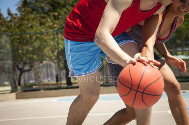 Jeune couple pratiquant le basket sur le terrain — Photo de stock