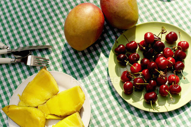 Вишні та манго на столі, вид зверху — стокове фото