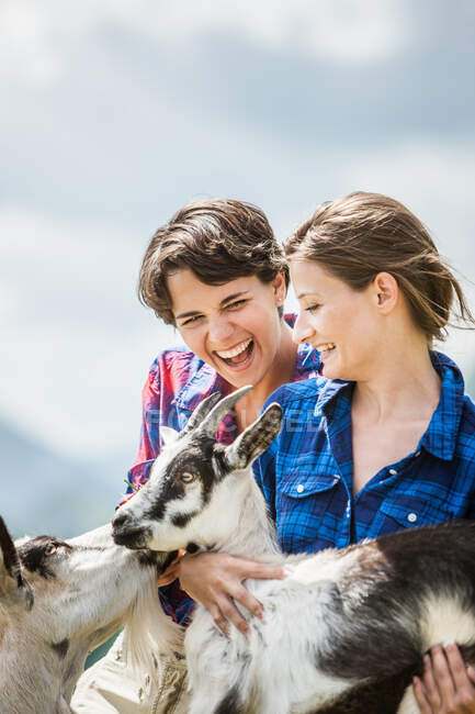 Mujeres jóvenes sosteniendo cabritos, Tirol, Austria - foto de stock
